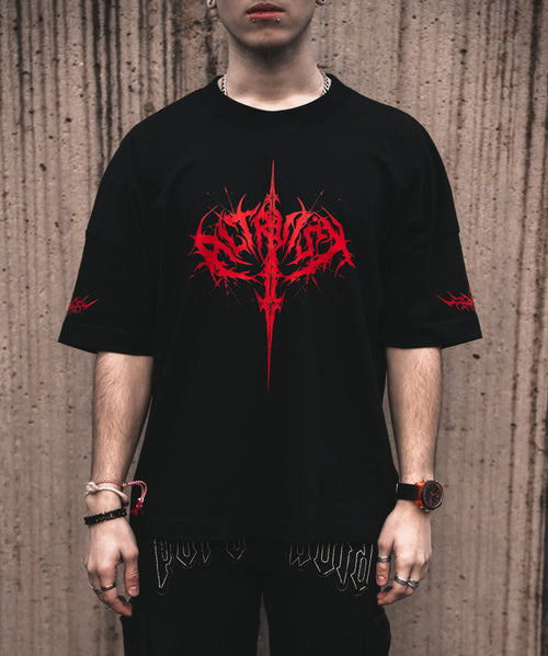 Front view of a model wearing the ALTRUIST black oversized t-shirt featuring a red neo-tribal cyber-sigilism graphic on the chest and sleeves, styled with black cargo pants.